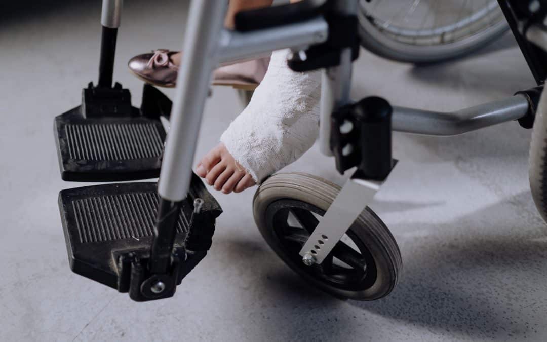 Person mit Gipsfuß in Rollstuhl als Symbol für lange Krankheit